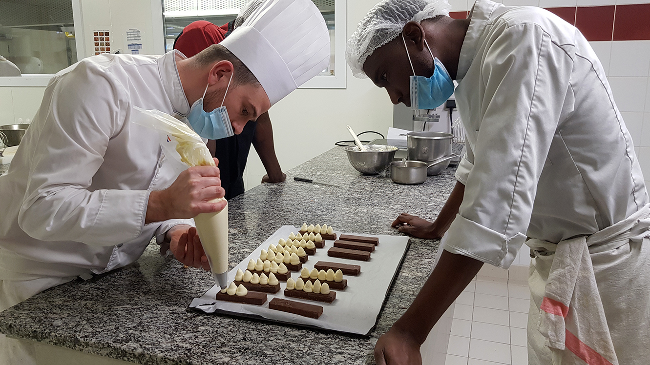 Une photographie d'un formateur et d'un formé, en train d'apprendre à réaliser des desserts.